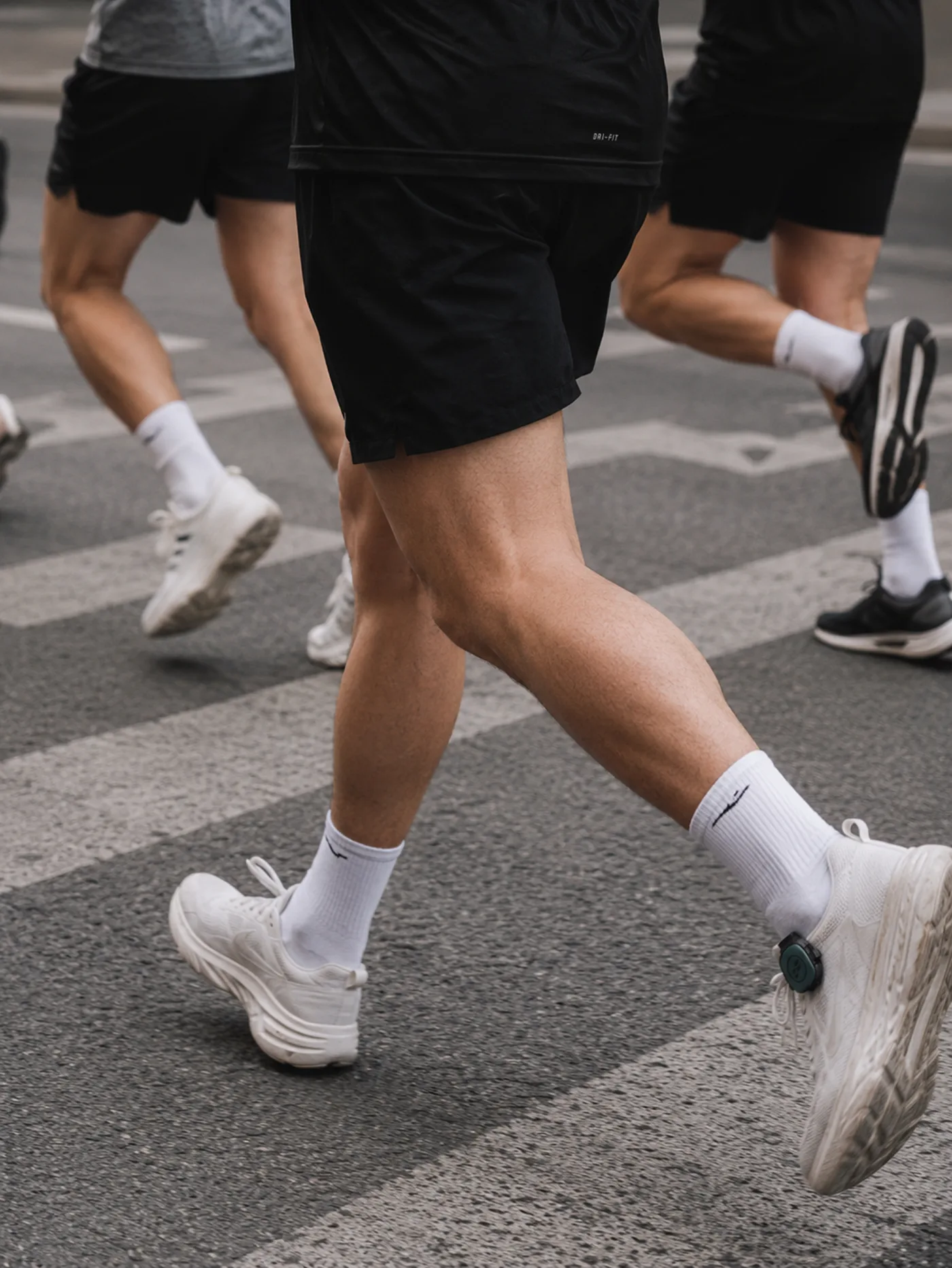 Runners crossing a city street wearing STRIV pods
