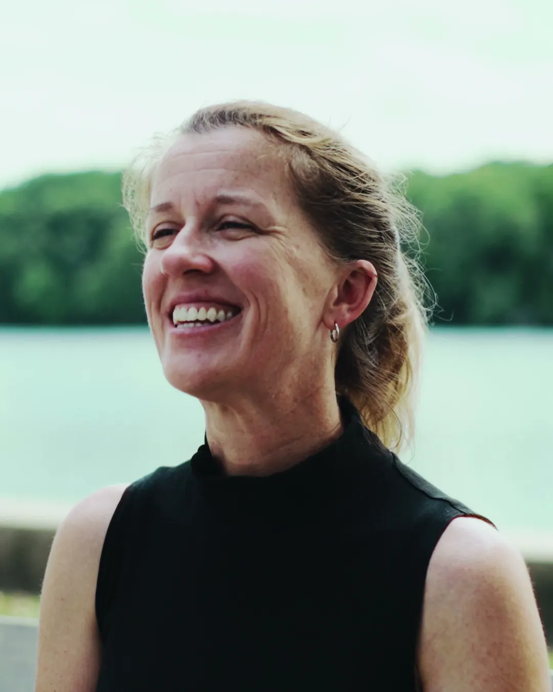 A runner smiling by the water after a run.